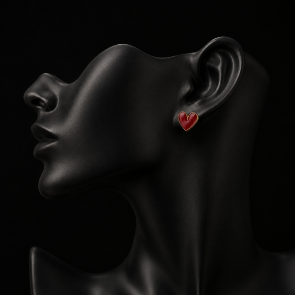 Red heart earring with gold-tone edge on a black mannequin ear