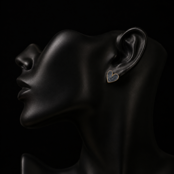 Dark heart earring with gold-tone edge on a black mannequin ear