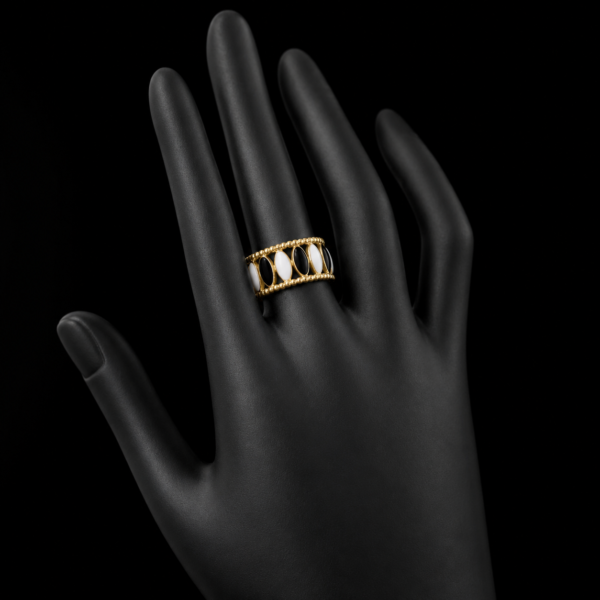 Gold black and white stone ring on upright black hand