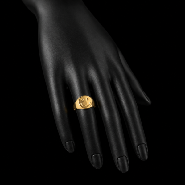 Gold smiley face signet ring on downward black hand display
