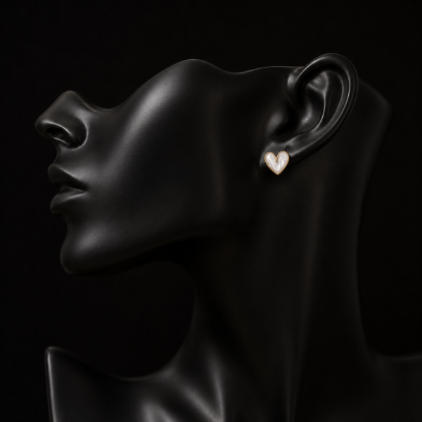 White heart earring with gold-tone edge on a black mannequin ear