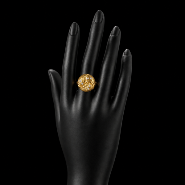 Gold swirl crystal ring on upright black hand