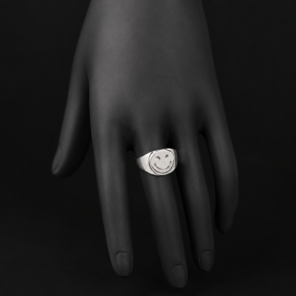 Silver smiley face signet ring on downward black hand display