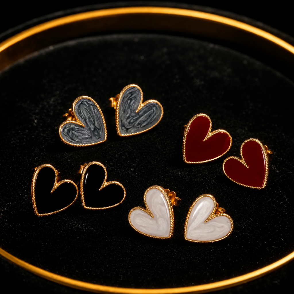 Heart-shaped earrings in black, red, white and gold on a black tray