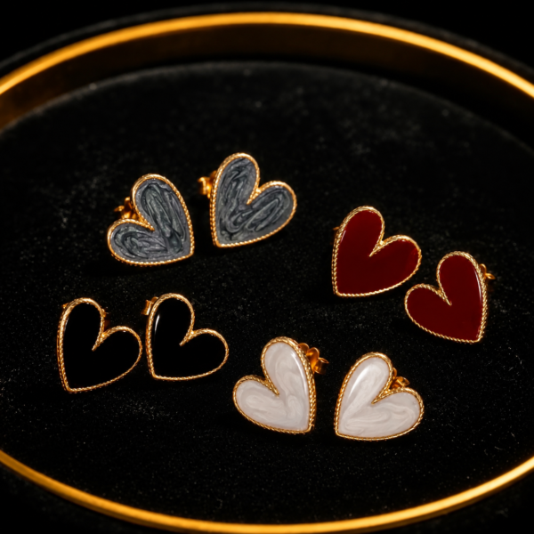 Heart-shaped earrings in black, red, white and gold on a black tray