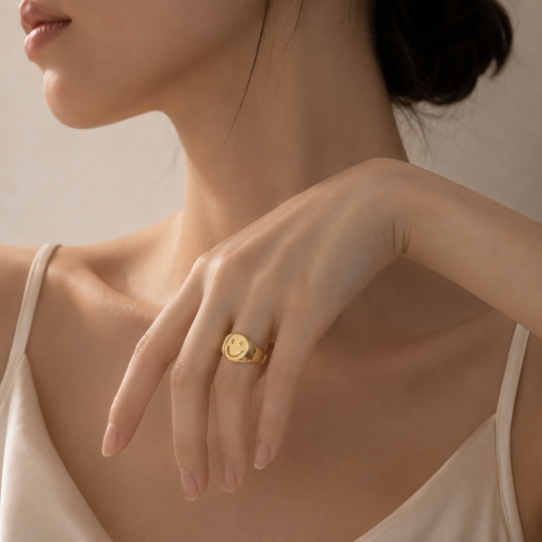 Female model wearing gold smiley face signet ring