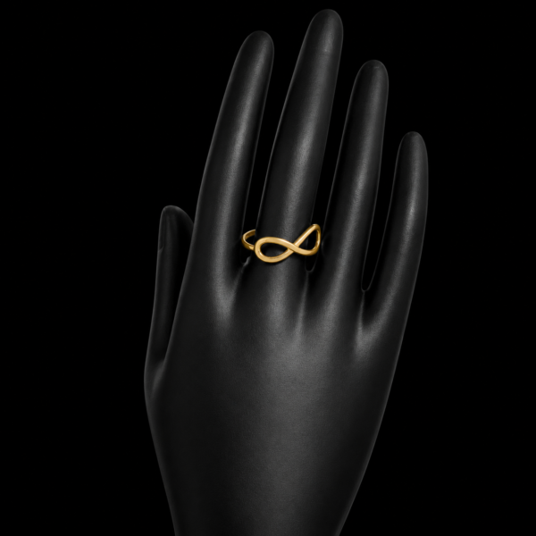 Gold infinity ring on upright black hand display