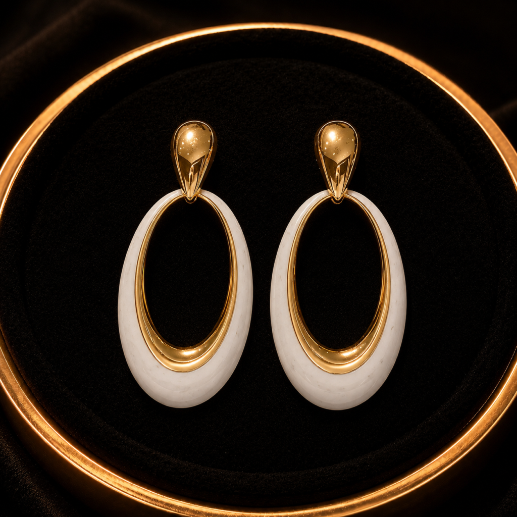 White oval drop earrings with gold-tone accents on a black tray