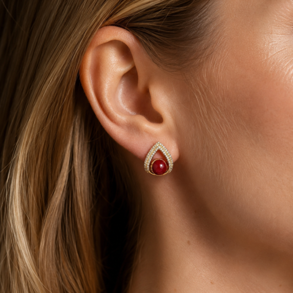 Close-up of a red teardrop stud earring worn on the ear