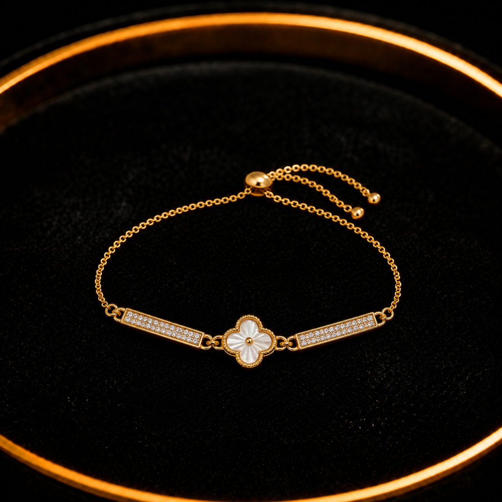 Gold-tone clover bar bracelet with white center detail on a black tray