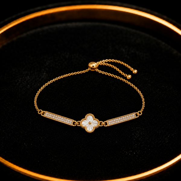 Gold-tone clover bar bracelet with white center detail on a black tray