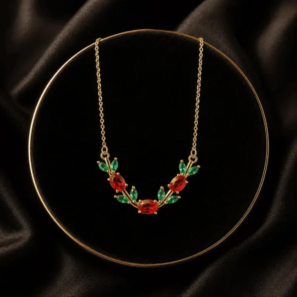 Red and green floral leaf crystal-style necklace arranged on black fabric
