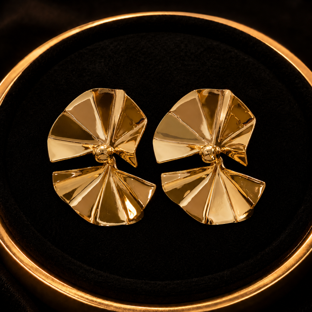 Gold-tone folded petal earrings on a black jewelry tray