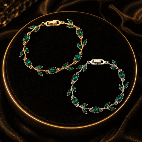 Two green leaf crystal-style bracelets arranged on black fabric