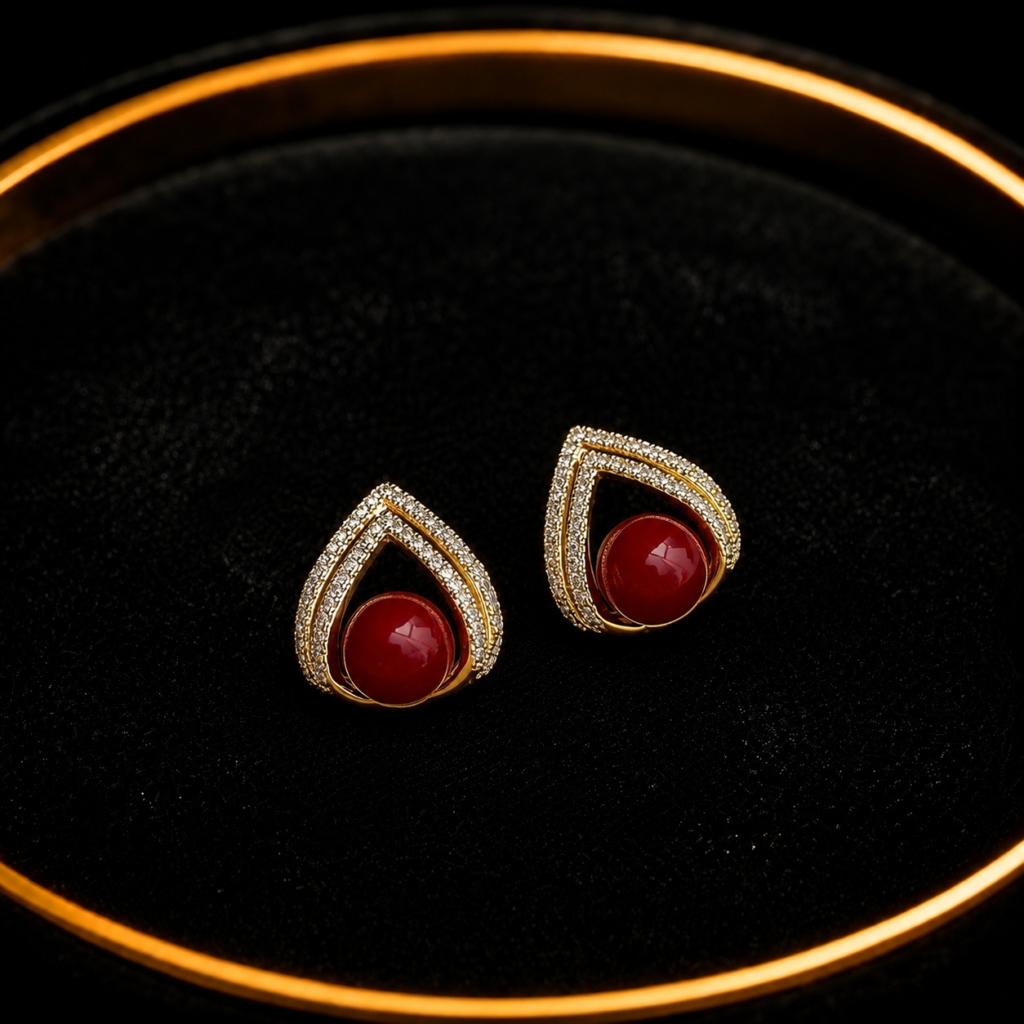 Red teardrop stud earrings with crystal border on a black tray
