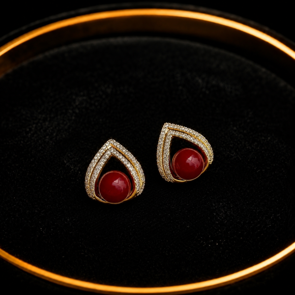 Red teardrop stud earrings with crystal border on a black tray