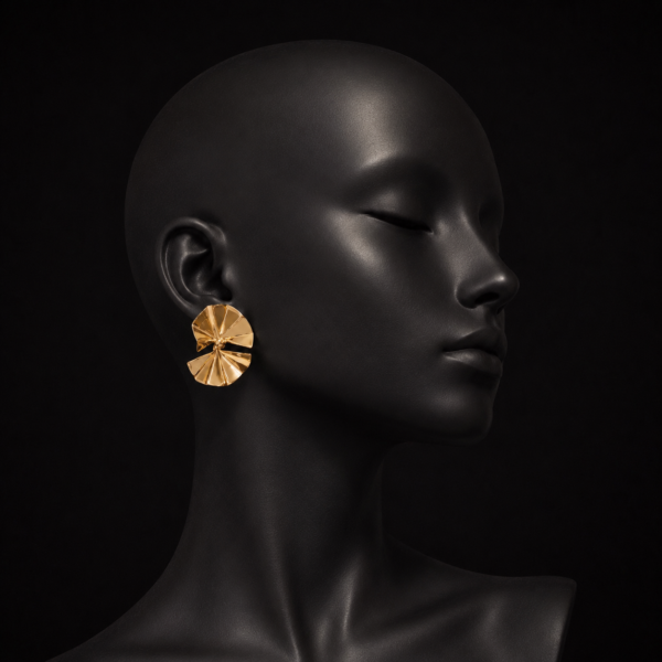 Gold-tone folded petal statement earrings displayed on a black mannequin