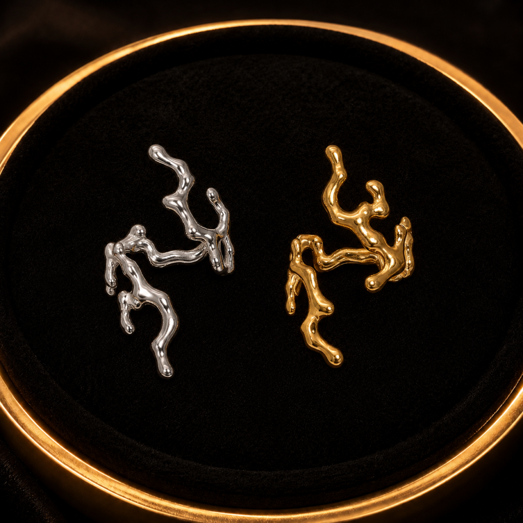 Silver-tone and gold-tone branch statement earrings on a black tray